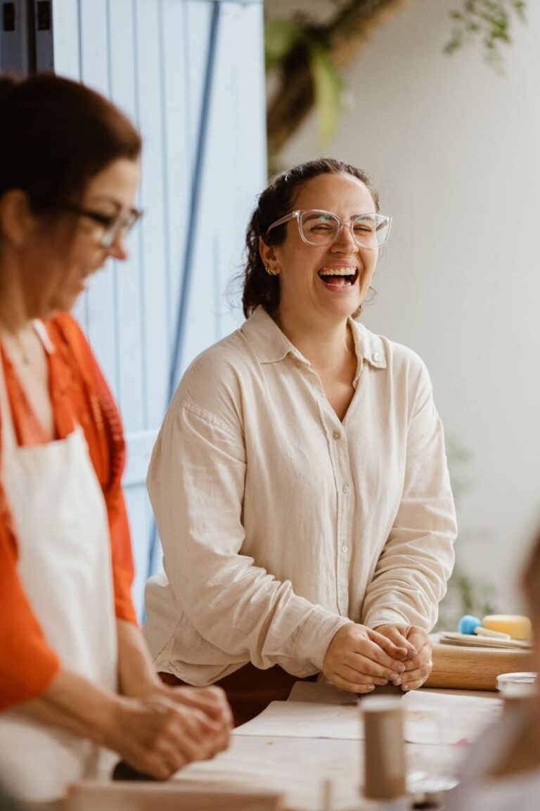 Two women enjoying a baking session indoors, laughing and sharing moments of togetherness.